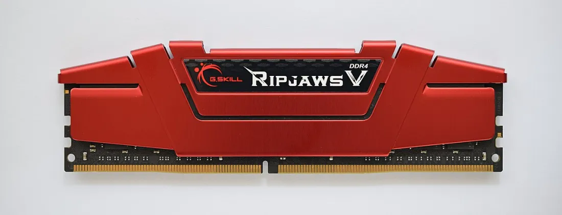 A red DDR4 RAM module: a long thin circuit board with memory chips under a heat spreader and gold contacts along the bottom edge.