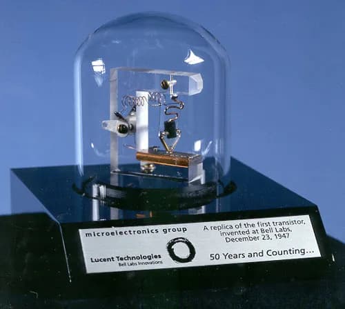 A replica of the first transistor under a glass dome: a small triangle of plastic with wires touching a piece of germanium.