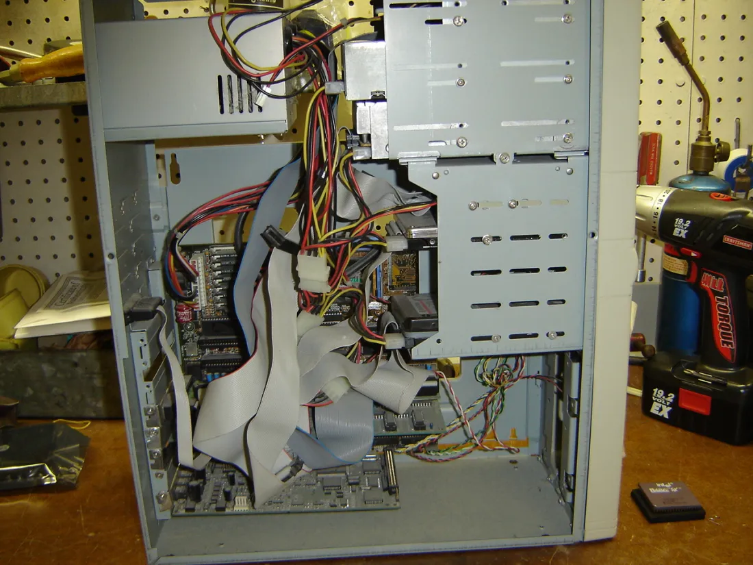 The inside of a desktop computer with its side panel removed, showing the power supply, motherboard, drive bays and many cables.