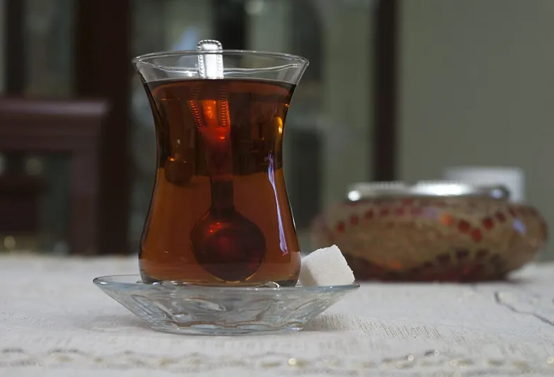 A glass cup of amber tea on a saucer